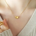 Elegante collana con ciondolo a chicco d'oro da donna, indossata da una modella in stile minimal - Oro