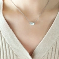 Collana minimalista con ciondolo a chicco d'argento lucido indossata da una modella - Color Acciaio