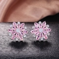 Macro view of pink sunflower stud earrings with cubic zirconia on black leather - Silver + Pink