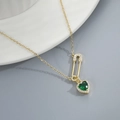 Macro detail of gold safety pin pendant with a sparkling green heart-shaped gemstone - Gold Green
