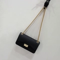 Schwarze Mini-Umhängetasche mit V-Steppmuster und Goldkette an der Wand hängend - Groß / Schwarz