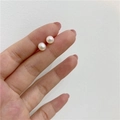 Close-up of small natural freshwater pearl earrings held on a finger for size scale - Small (Approx. 6mm)