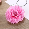 Close-up of a pink synthetic peony hair clip with layered petals on a wooden background - Pink