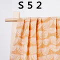 Ginger yellow muslin baby blanket with white semi-circle patterns on wooden stand - Ginger White Wave