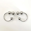 Detalle de pendientes de aro plateados en forma de C con esferas metálicas pulidas - Plateado