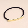 Primer plano de una goma negra para el pelo con un elegante adorno de metal dorado curvo - Coletero de borde fino Dorado
