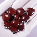 Natural red jasper heart-shaped pendants with metal clasp held in a gloved palm - Rainbow