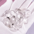 Translucent heart-shaped agate pendants with silver loops on a gloved hand - Clear Quartz