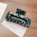 Detail of a rectangular acetate hair claw clip with dark green marble texture patterns - Large / Green