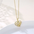 Detalle de colgante de corazón dorado con texto LOVE y circonitas en plato blanco - Letra Love Corazón Estrella / Dorado