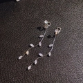 Makro-Detail von Blatt-Zirkon-Ohrclips mit langen Quasten und silbernen Ketten - Clip-on-Stil (ohne Piercing) / Ein Paar