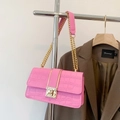 Detailed view of pink croc-embossed shoulder bag with gold chain strap on a blazer - Pink