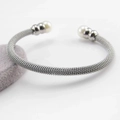 Detalle de brazalete plateado de malla con perlas blancas sobre soporte de terciopelo - Color Acero