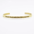 Close-up of gold 4mm stainless steel cuff bracelet engraved with Beach Soul text - Beach Soul with the little starfish