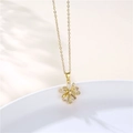 Close-up of gold flower pendant necklace with zircon stones on a white ceramic plate - Gold