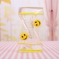 Detail van de gele vloeibare zandloper met smileywielen op geruit tafelkleed - Geel lachend gezicht