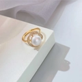 Golden micro-pave diamond and pearl ring displayed on a white minimalist pedestal - Gold - Wrapped Pearl Ring