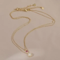 Macro shot of double-layer gold necklace featuring ruby-red and white zircon pendants - Gold
