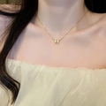 Close-up of a gold-plated necklace with a shell H-letter pendant on a model's neck - Gold Letter H (12# Necklace)