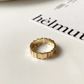 Dettaglio macro anello dorato con texture a ingranaggi e zirconi incastonati a mano - Oro-Blocco Rettangolare