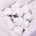 White heart-shaped natural agate stone pendants with metal bails held in hand - White Jade