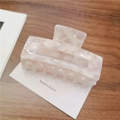 Detail of a large cream-colored acetate hair claw clip with marble texture on wooden background - Large / Pink & White