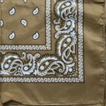 Close-up of brown paisley bandana fabric showing white and black cashew flower patterns - Khaki