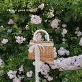Handgewebte Strohtasche mit weißem Spitzenbesatz und Schleife im Gartenambiente - Spitzenstil
