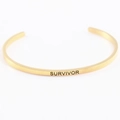Detail of golden stainless steel mantra bracelet with Survivor engraved lettering - SURVIVOR