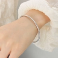Minimalist silver-finish titanium steel bangle worn over a white shirt cuff - Steel / M