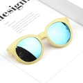 Detail einer gelben Kindersonnenbrille mit blau verspiegelten Gläsern auf einem Magazin - Gelber Rahmen Goldene Linse
