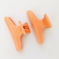 Dettaglio di due fermagli per capelli in plastica arancione su sfondo bianco - Arancione