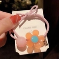 Pink sunflower hair tie with blue heart and orange petals on a white card display - Pink Small Flower Hair Tie