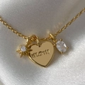 Collana Mom dorata con stella in zircone e ciondolo a cuore su sfondo in seta bianca - MOM