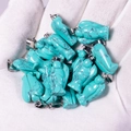 Multiple turquoise angel pendants with metal clasps held in a gloved hand - Synthetic Turquoise