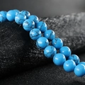 Round blue turquoise stone beads with natural black veins on a dark leather background - Black Line Blue Turquoise