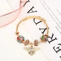 Detailed shot of golden spiral bead bracelet with colorful rhinestones and bee pendant - Gold Multicolor
