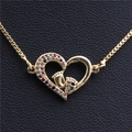 Detalle de un colgante de corazón dorado con circonitas de colores y pies de bebé en cuero - Pies de Bebé En el Corazón C