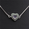Détail macro du collier cœur argenté avec zircons bleus et verts sur cuir noir - Coeur en Or Blanc E