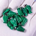 Bulk green malachite angel pendants with metallic rings held in a gloved hand - Malachite (Synthetic)