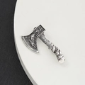 Broche de hacha vintage plateada con grabados detallados y mango con textura en plato blanco - Plateado