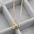 Primo piano della collana a corona dorata con zirconi colorati in una scatola di velluto - Corona B Oro