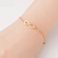 Detail of golden infinity symbol titanium steel bracelet worn on a female wrist - Infinity Symbol / Gold