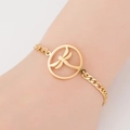 Detail of a gold titanium steel bracelet with a hollow dragonfly charm worn on the wrist - Dragonfly / Gold