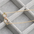 Detail of a gold infinity bracelet with multi-colored crystals in a jewelry box - Infinity Colorful Zirconia Necklace