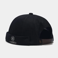 Detail of black docker cap with a metal leaf emblem and adjustable leather strap - Black With Letter Maple