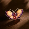 Detail of colorful butterfly brooch with purple gradient wings and red gemstone body - Purple Enamel Gradient