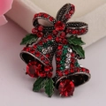 Detailaufnahme einer Weihnachtsglocken-Brosche mit roten Strasssteinen und grüner Emaille - Antiksilber