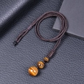 Macro view of woven tiger eye pendant on black leather background with sharp details - Yellow Tiger Eye Necklace