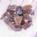 Hand holding various natural agate angel pendants with metal loops in multiple colors - Grey Agate